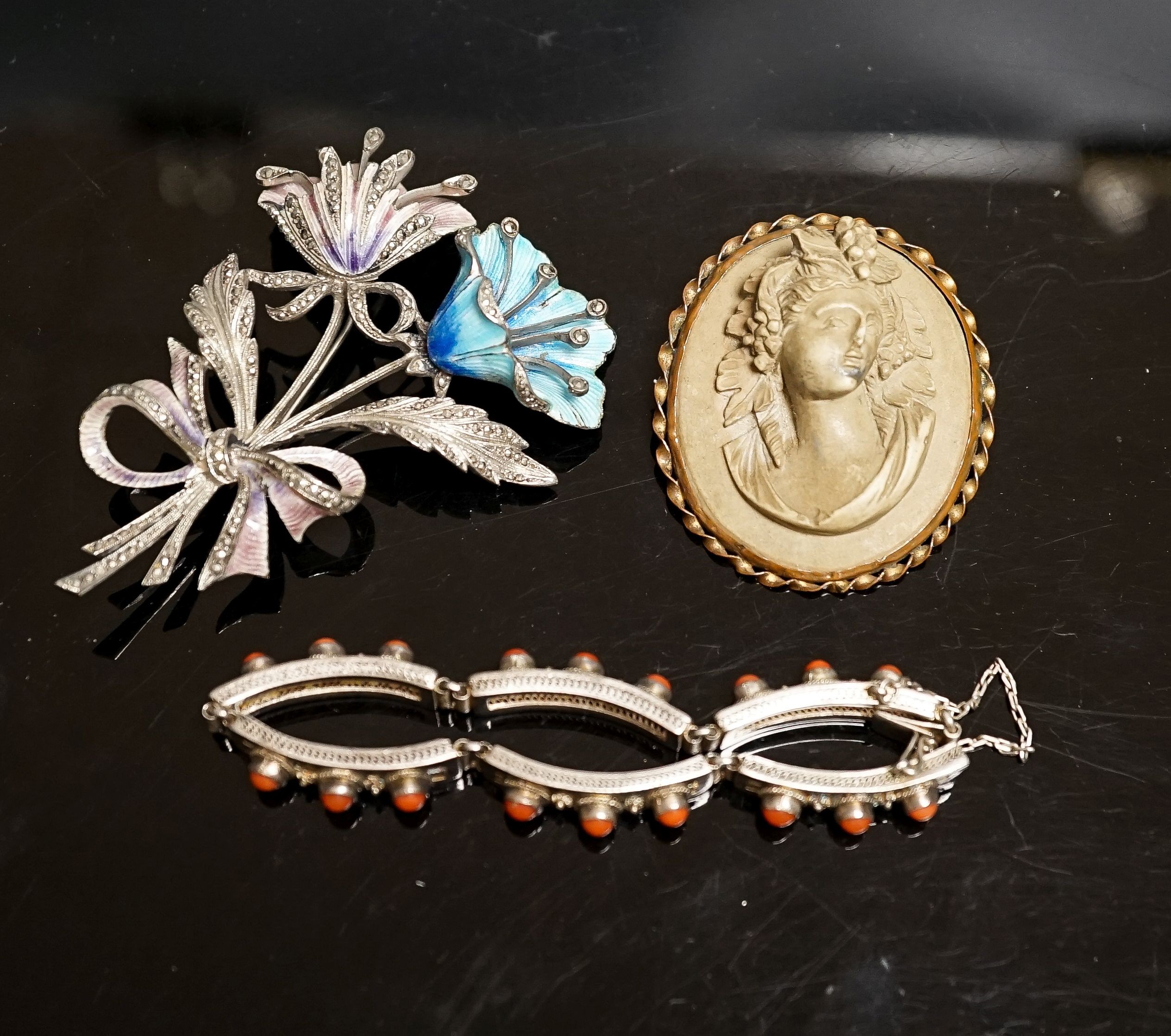 A 19th-century Lava cameo brooch, 49mm, a marcasite and enamel floral spray brooch and a coral mounted white metal bracelet.